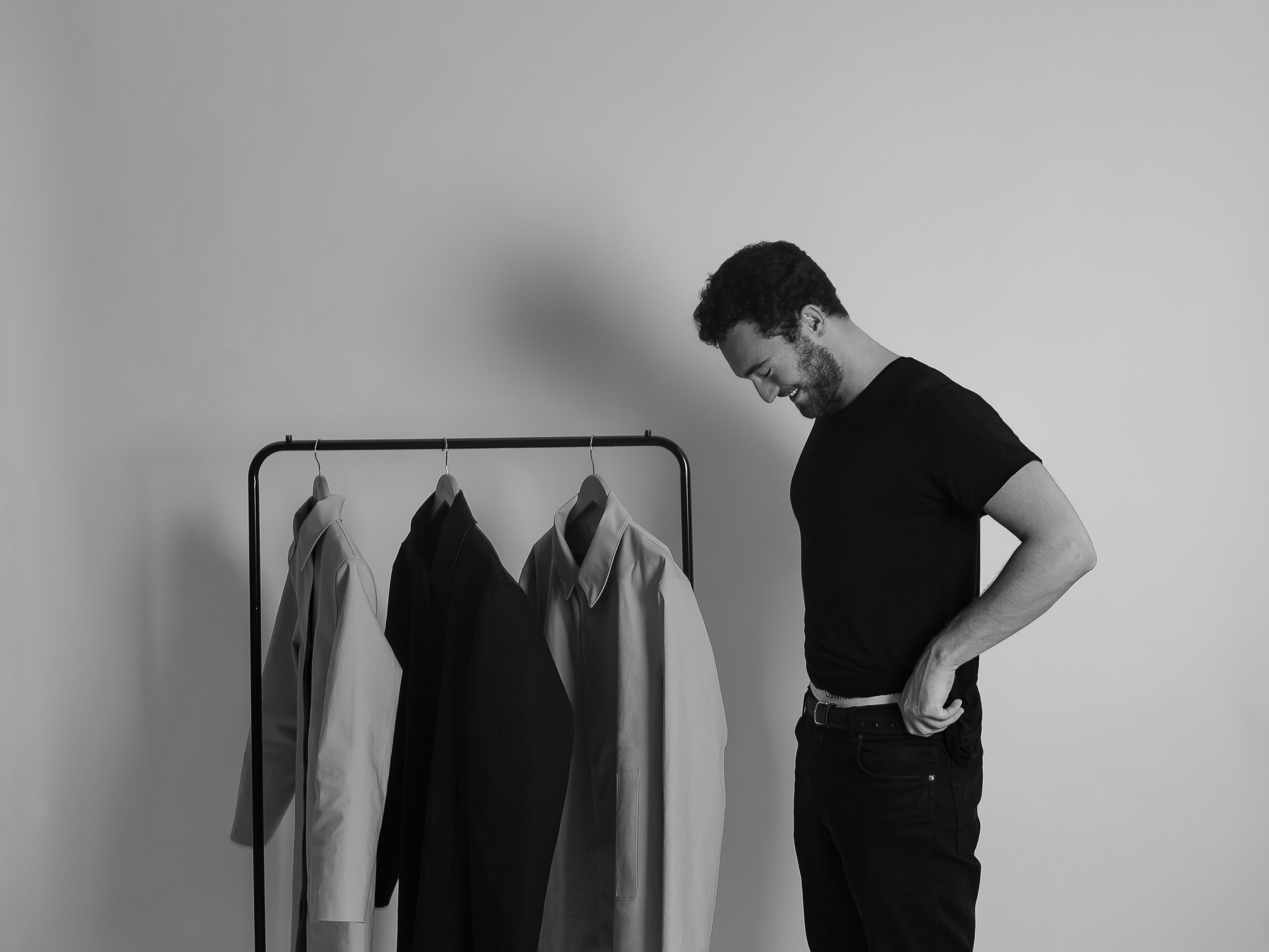 Faeroes founder standing next to rail of contemporary mackintosh raincoats